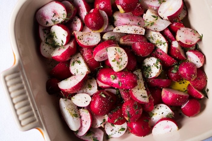 Raw halved radishes on a baking dish
