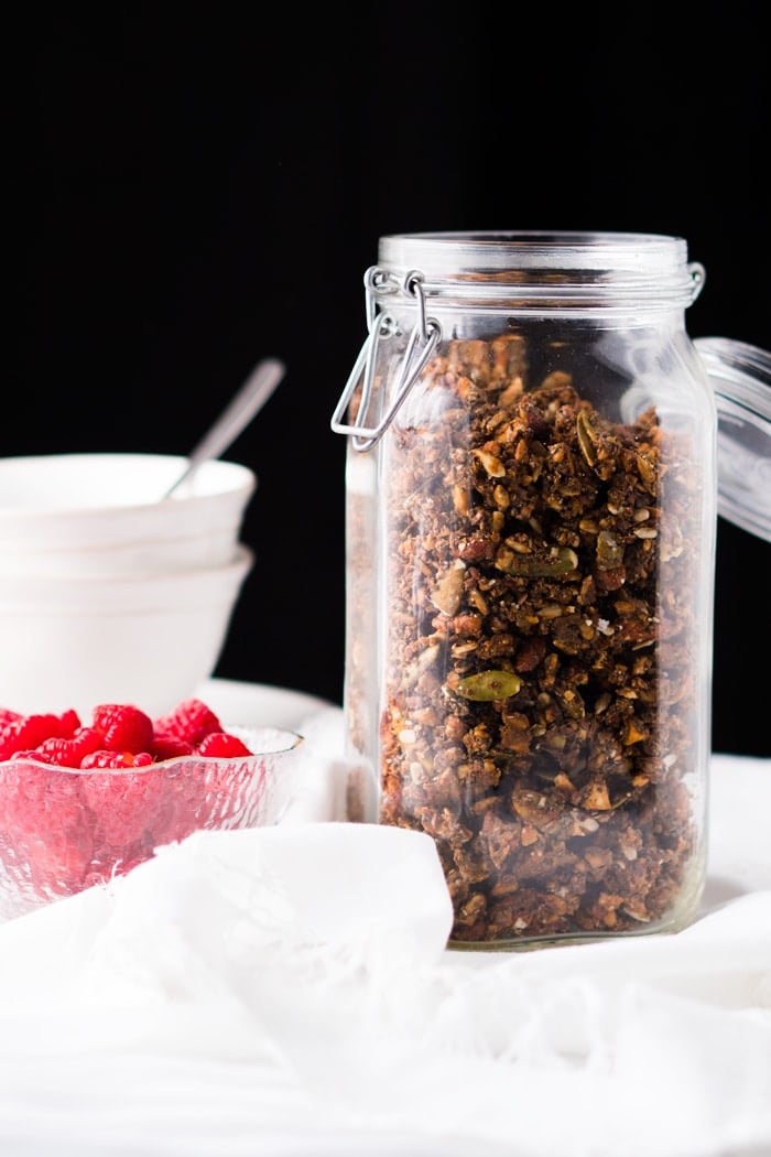 Keto granola in a glass container with a black background