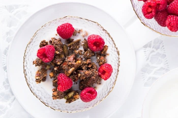 Keto granola in a bowl with raspberries and milk