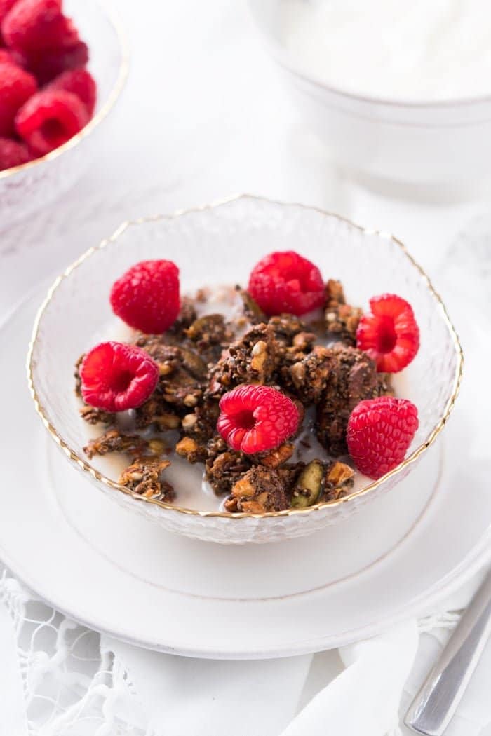 Keto granola in a bowl with raspberries and milk