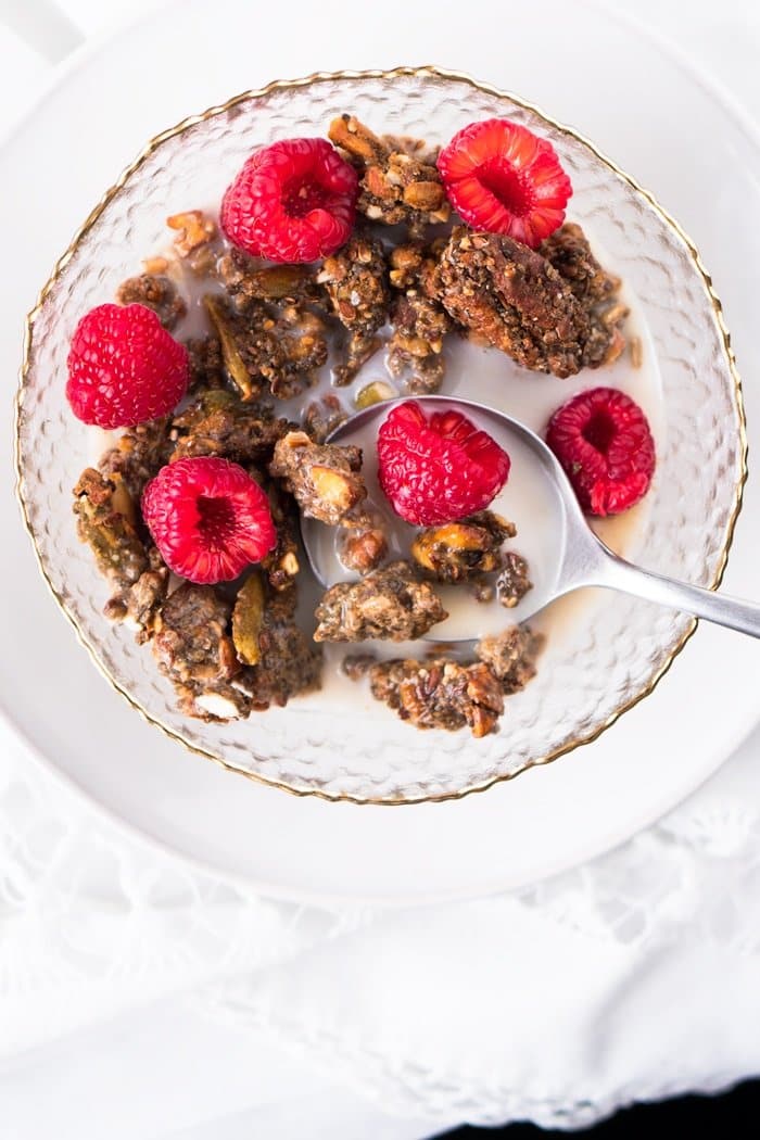 Keto granola in a bowl with raspberries and milk