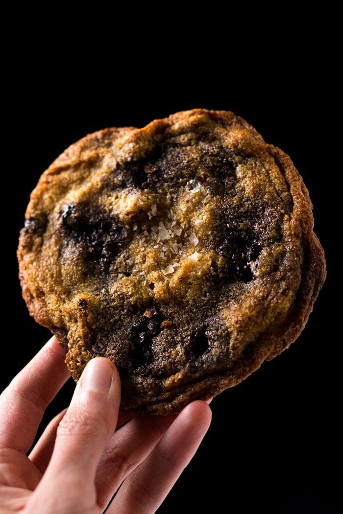 Holding a large keto chocolate chip cookie with flaky sea salt