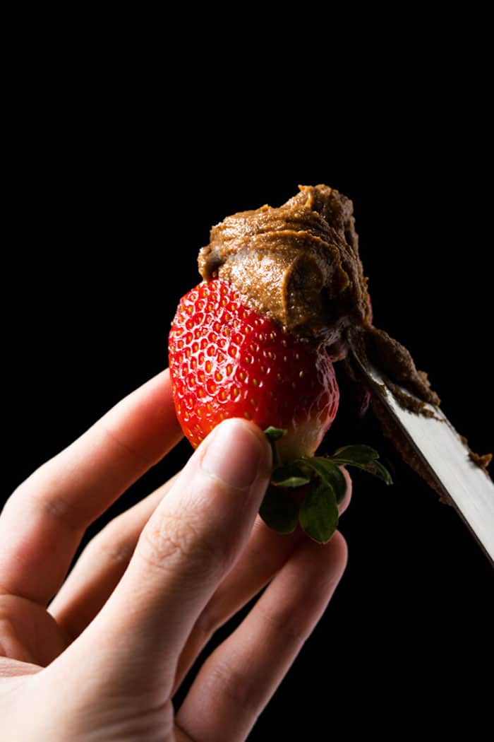 Smearing keto speculoos cookie butter on a strawberry