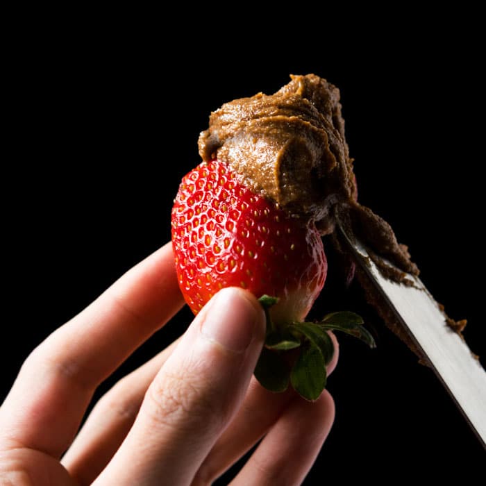 Smearing keto speculoos cookie butter on a strawberry