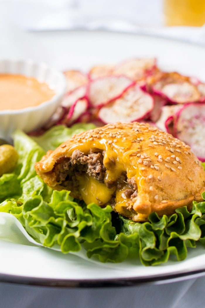 A keto cheeseburger on a plate with lettuce and 'fries'
