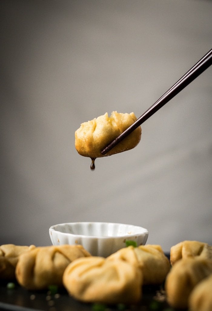 An action shot of a keto dumpling dipped in soy sauce