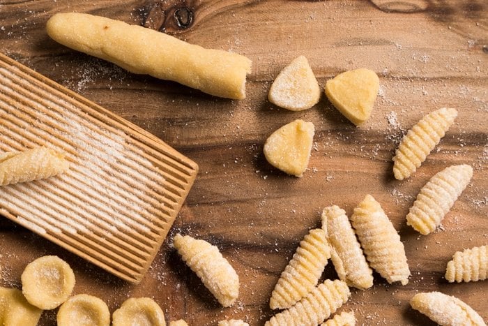 Cutting and shaping keto gnocchi on a wooden board