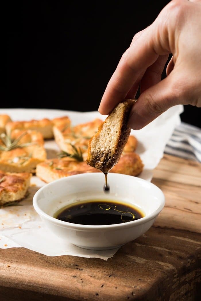 Dipping a slice of keto focaccia in olive oil and balsamic vinegar
