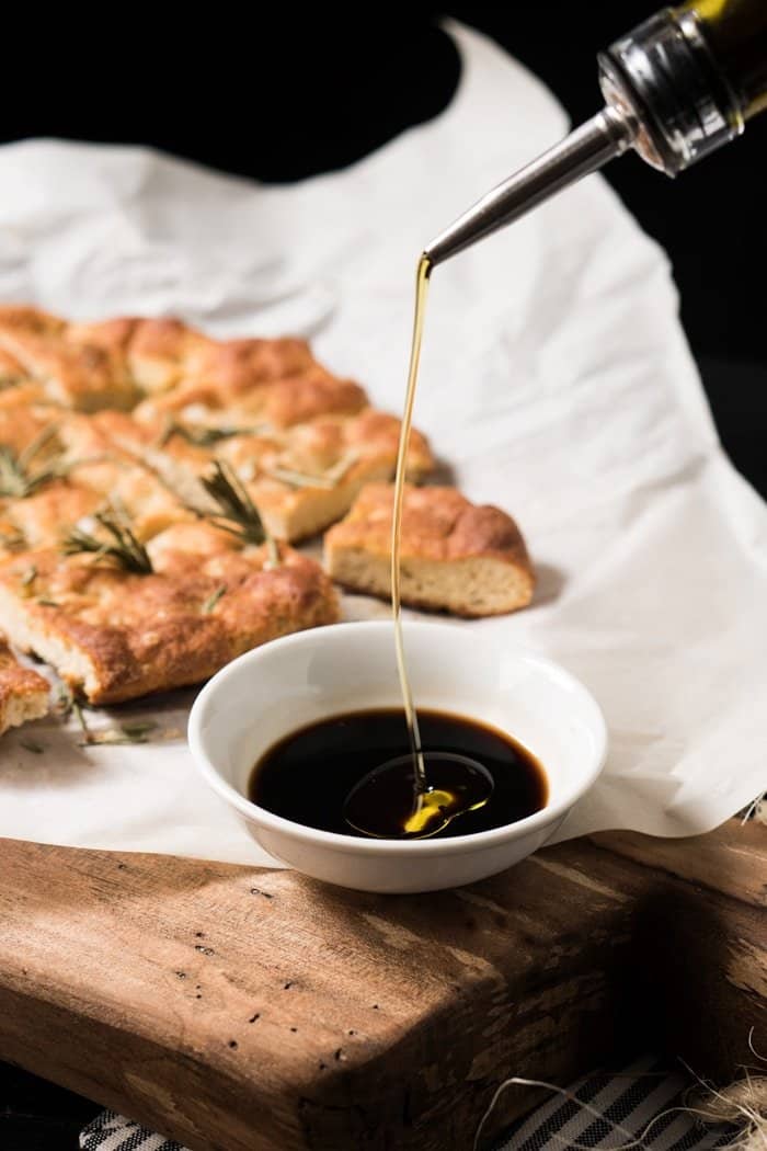 Drizzling extra virgin olive oil onto a dish with balsamic vinegar
