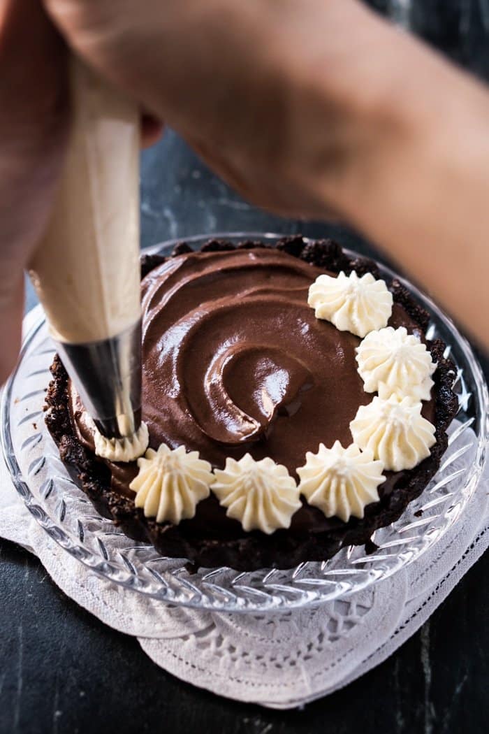 Piping whipped cream onto a keto French silk pie