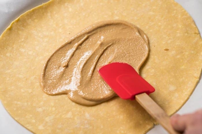 Spreading peanut butter onto keto pie crust