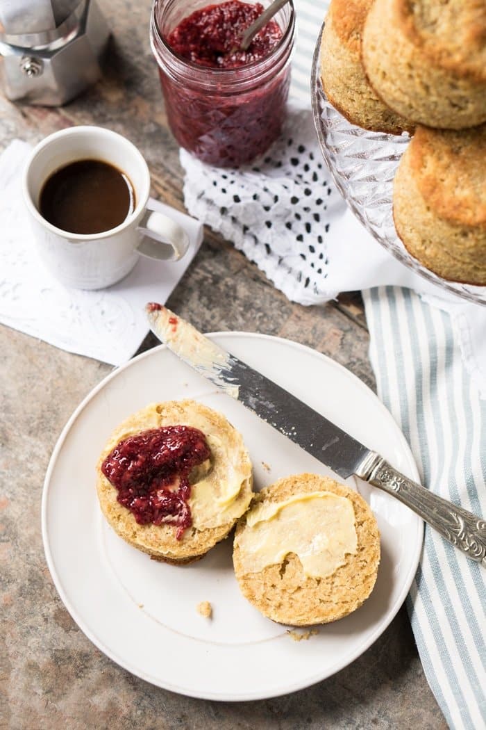A halved keto biscuit with butter and chia jam, with cup of coffee