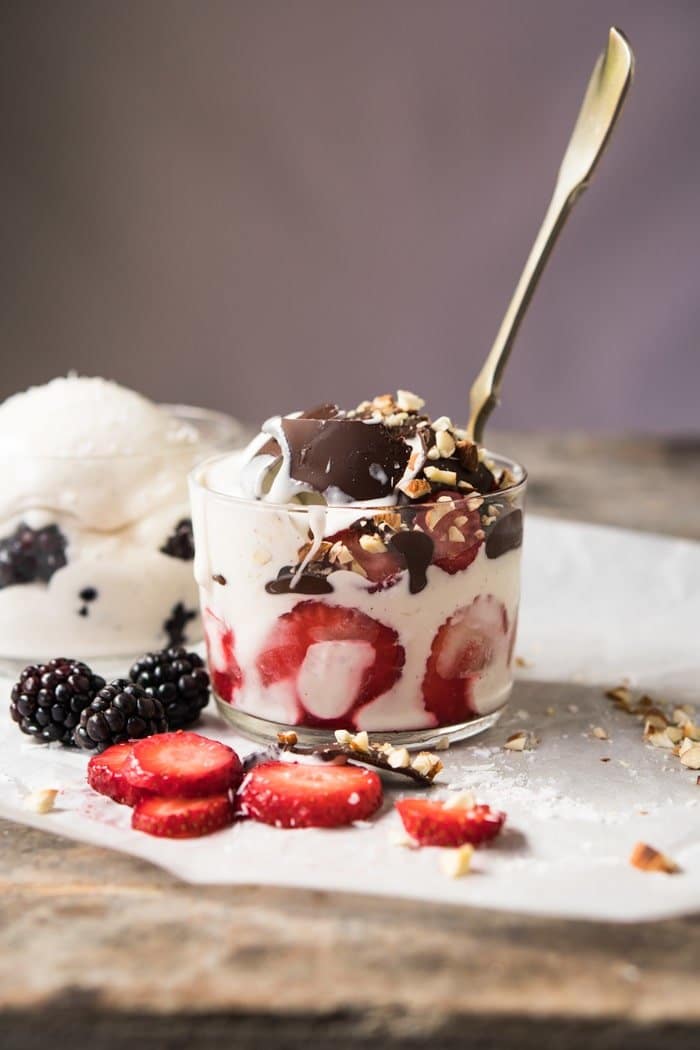 A glass with keto frozen yogurt, strawberries and a spoon