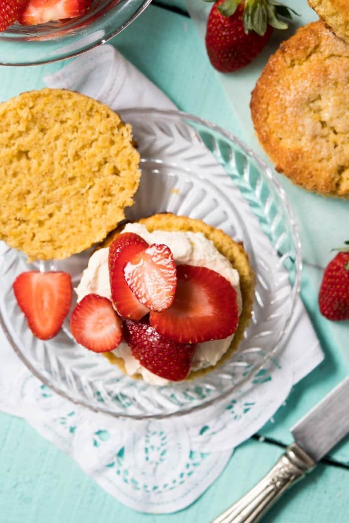 Adding whipped cream and strawberry slices to a halved shortbread