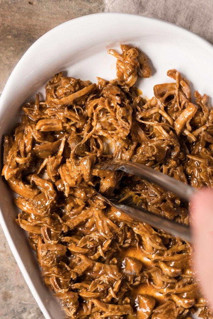 Shredding instant pot keto pulled pork in a white tray