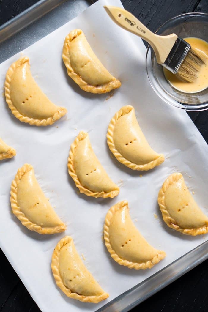 Brushing unbaked keto empanadas with egg wash