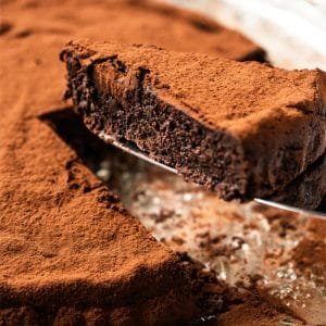 Cutting a slice of a fudgy keto flourless chocolate cake