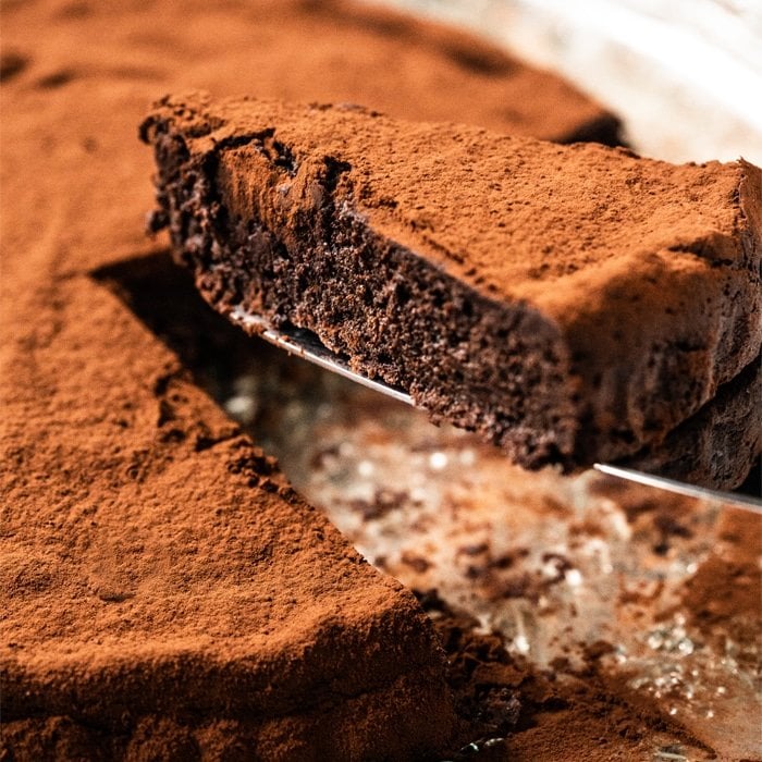 Cutting a slice of a fudgy keto flourless chocolate cake