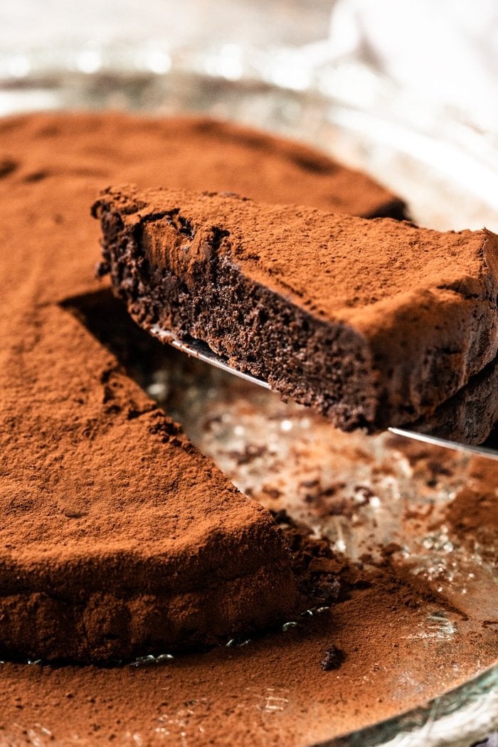 Cutting a slice of a fudgy keto flourless chocolate cake