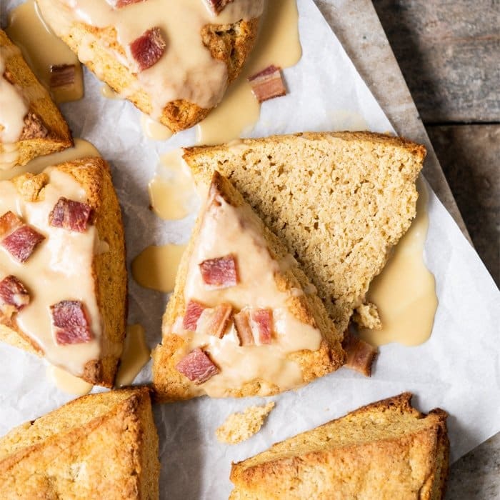 Sliced freshly baked keto scone with maple glaze and bacon, surrounded by uncut scones