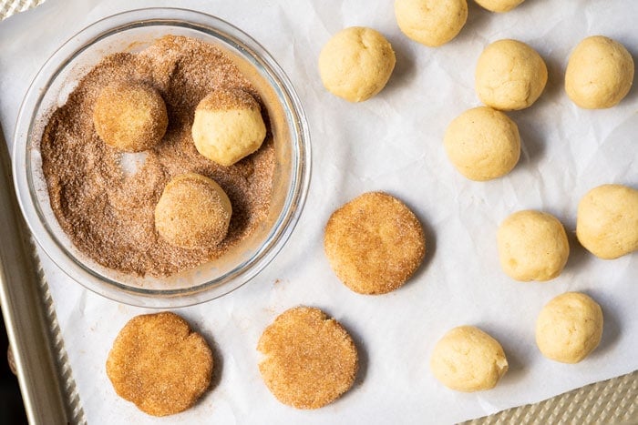Rolling keto snickerdoodle cookies in cinnamon sugar