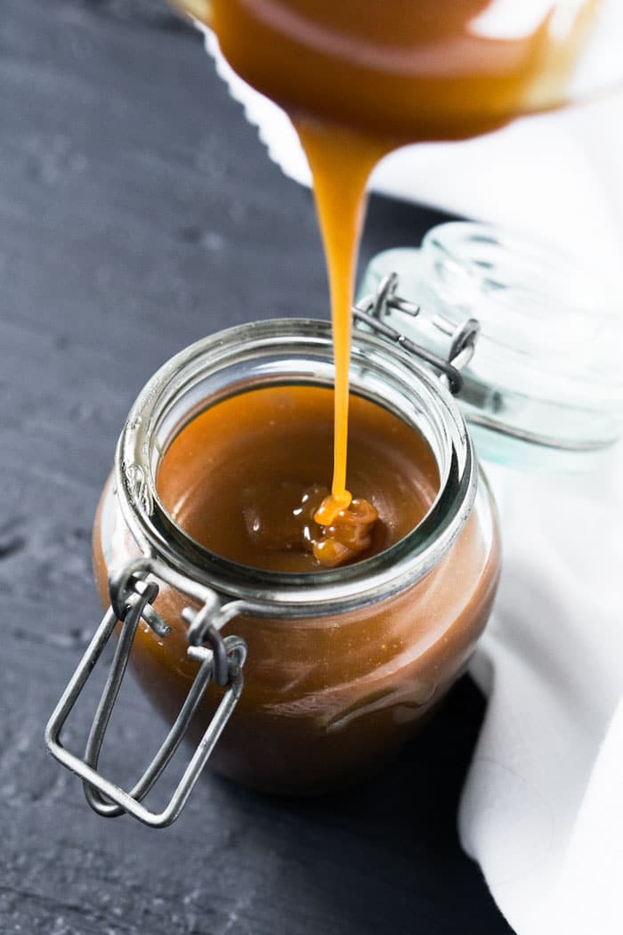 Pouring freshly made keto caramel sauce into a glass jar