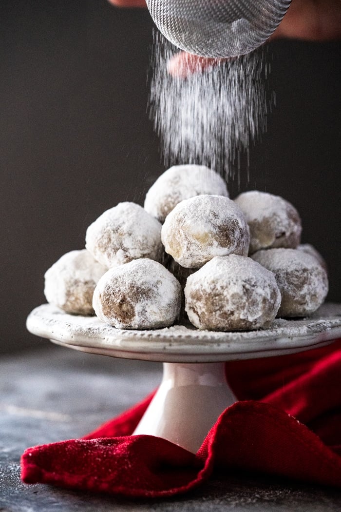 Dusting keto snowball cookies with powdered sweetener