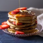 A stack of keto pancakes with sugar free syrup and strawberry slices