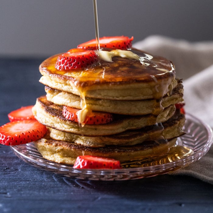 A stack of keto pancakes with sugar free syrup and strawberry slices