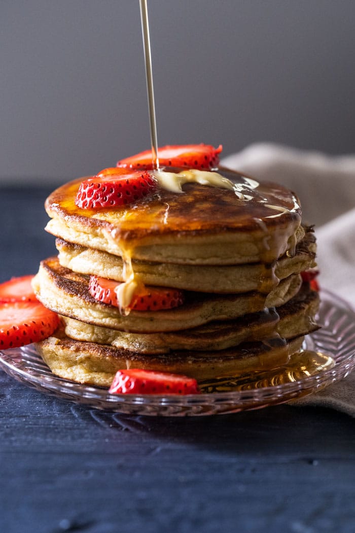 A stack of keto pancakes with sugar free syrup and strawberry slices