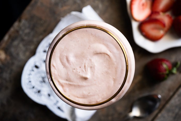 Overhead shot of cheesecake in a serving glass with strawberry slices
