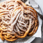 Keto funnel cakes with powdered 'sugar', on a plate with a fork