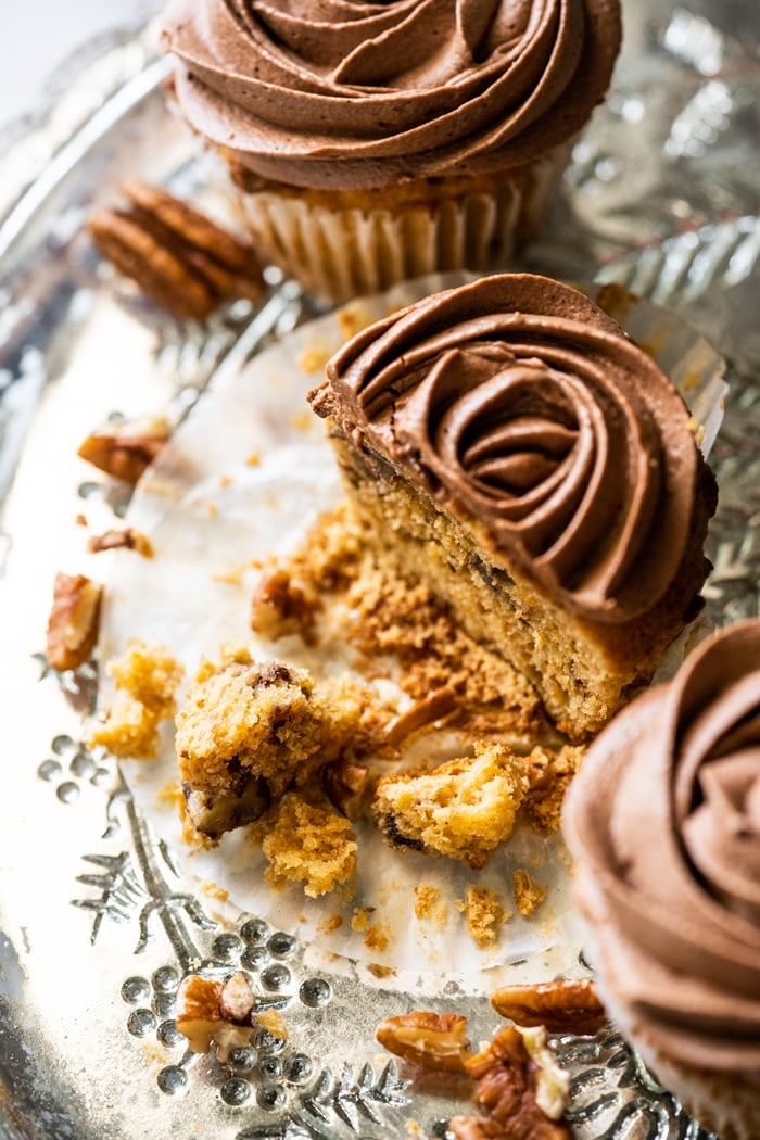 Halved keto banana cupcake with chocolate frosting and pecans