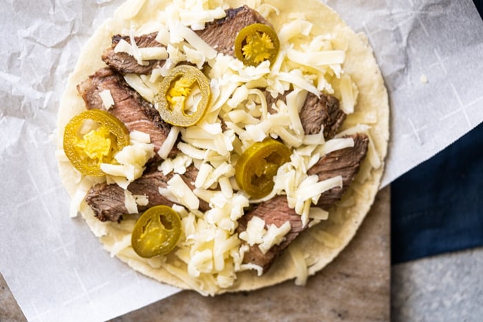 Assembling the keto quesadillas with tortillas, cheese, steak and jalapeños
