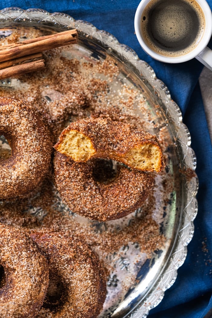 Keto apple cider donuts on a silver platter with a mug of coffee