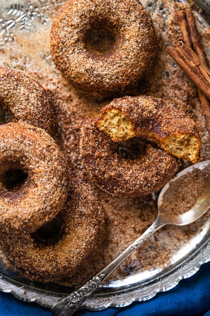 Rolling keto apple cider donuts in cinnamon sugar coating