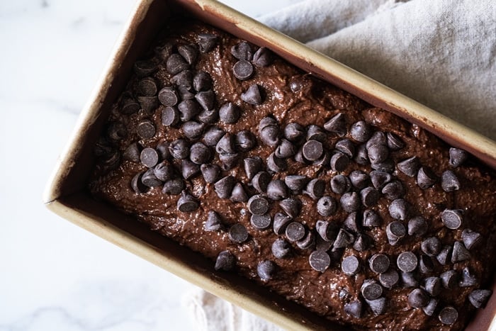 Unbaked paleo and keto chocolate zucchini bread in a golden mold with chocolate chips