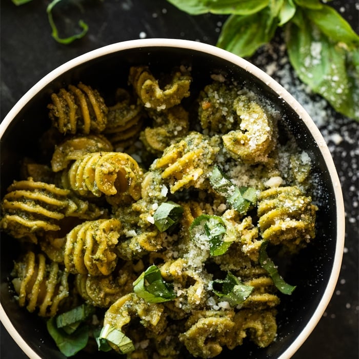 Keto pesto pasta with fresh basil and parmesan cheese in a black bowl