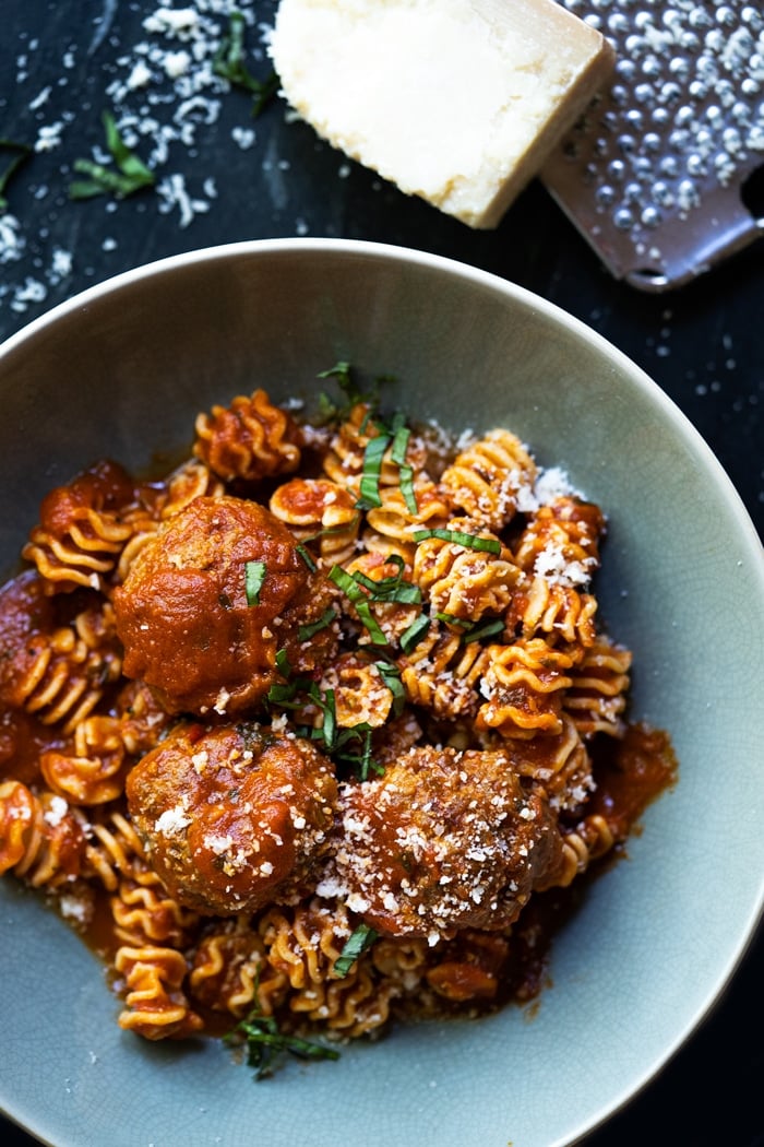 Bowl of Keto meatballs with radiatori pasta, Parmesan cheese and basil