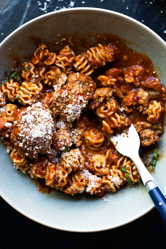 Eating a bowl of low carb meatballs and pasta with a fork