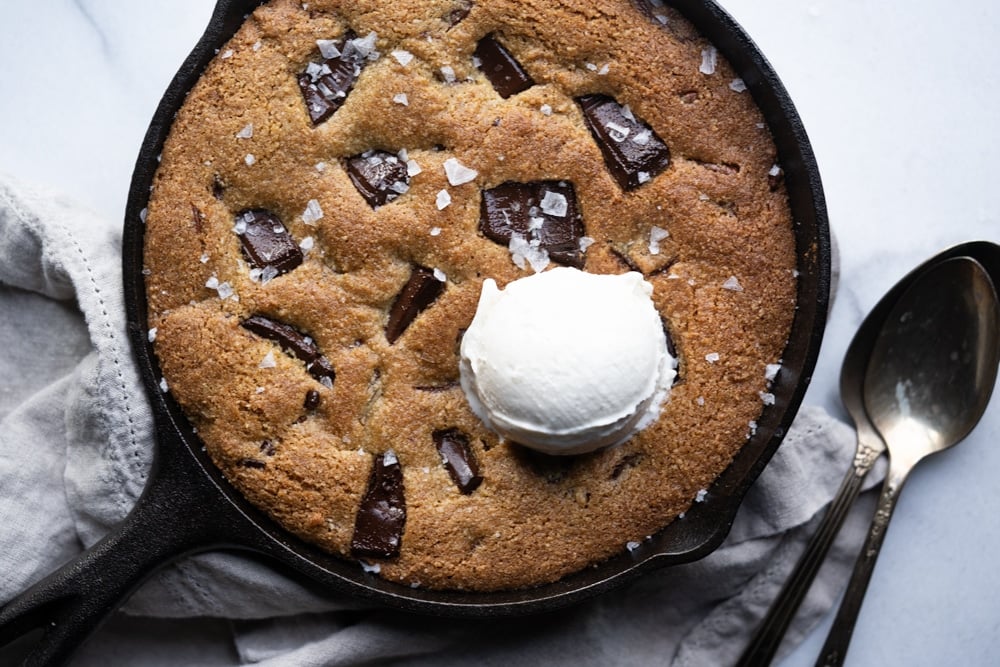 Freshly baked keto skillet cookie with a scoop of vanilla ice cream and flaky sea salt