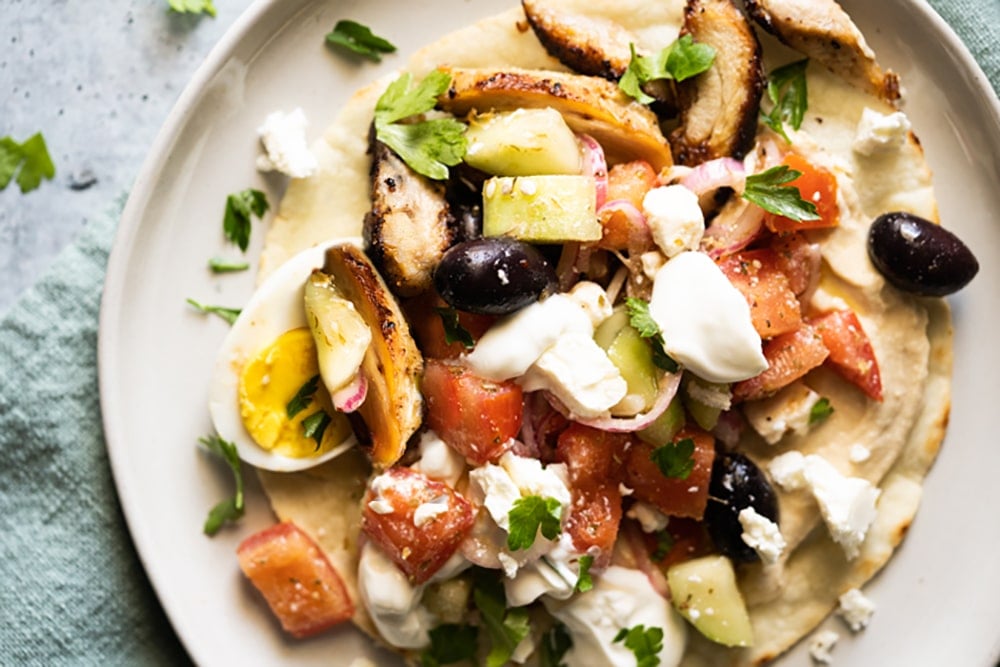 A paleo and keto chicken wrap with tomatoes, cucumber, hard-boiled egg, feta and olives