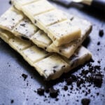 Broken up Keto Cookies 'n' creme candy bar with cookie crumbles around