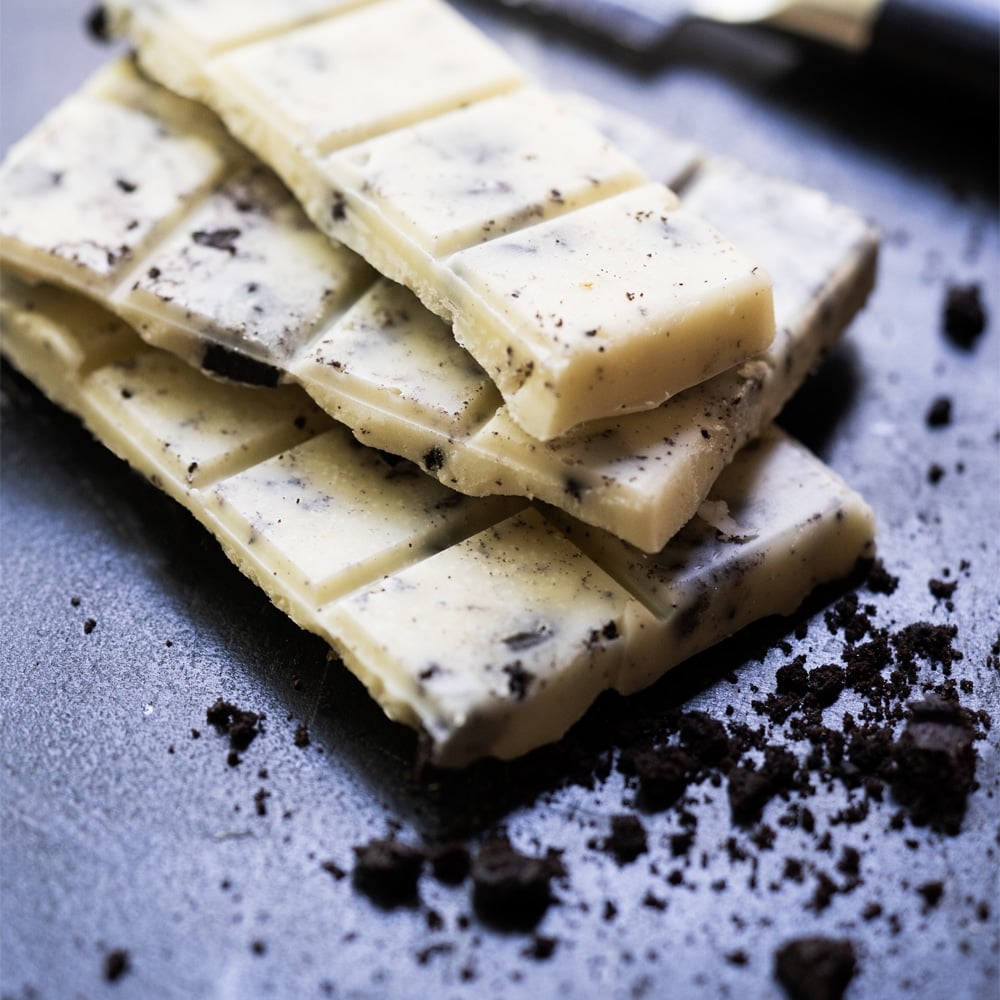 Broken up Keto Cookies 'n' creme candy bar with cookie crumbles around
