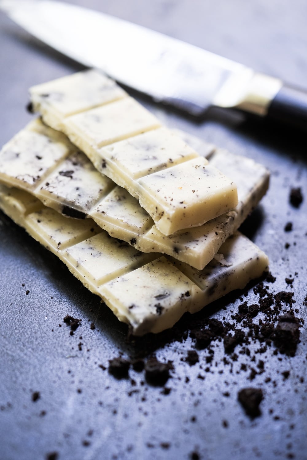 Broken up Keto Cookies 'n' creme candy bar with cookie crumbles around 