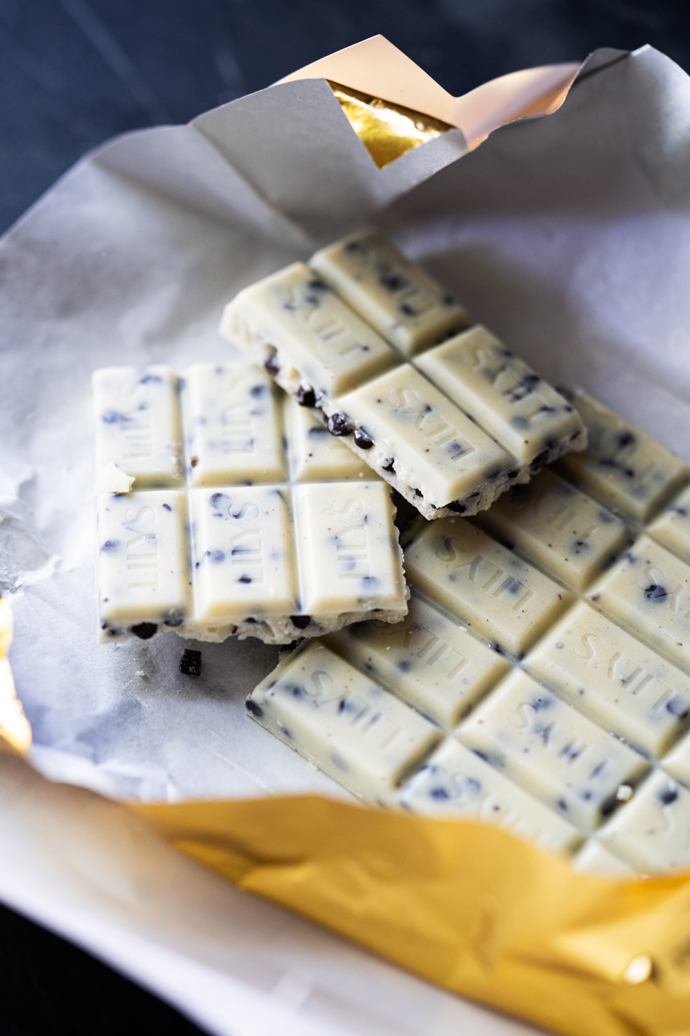 Broken up Lily's Keto Cookies 'N' Creme Candy Bars in gold foil wrapping
