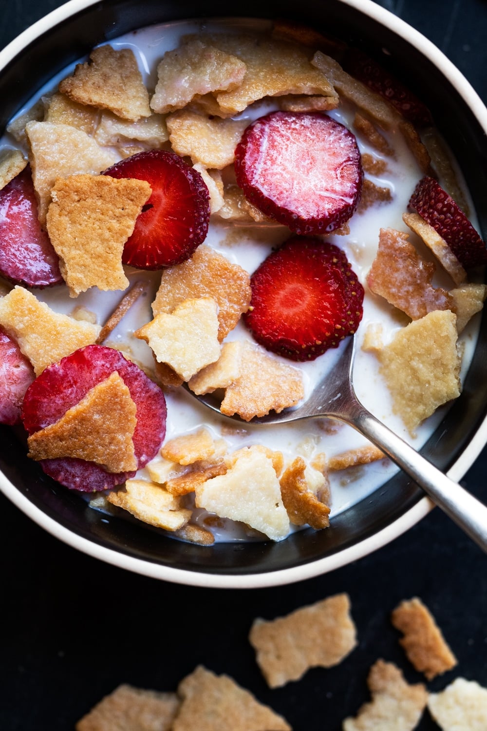 Keto Frosted Flakes cereal with sliced strawberries and almond milk in a black bowl
