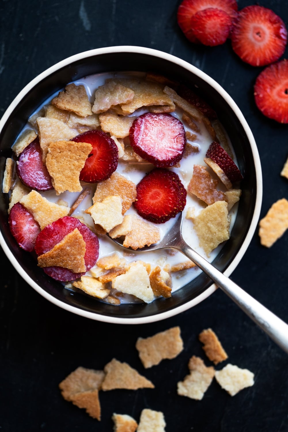 Keto Frosted Flakes cereal with sliced strawberries and almond milk in a black bowl