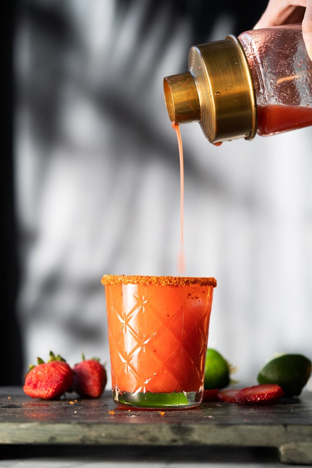 Pouring a paleo and keto strawberry margarita from a glass shaker