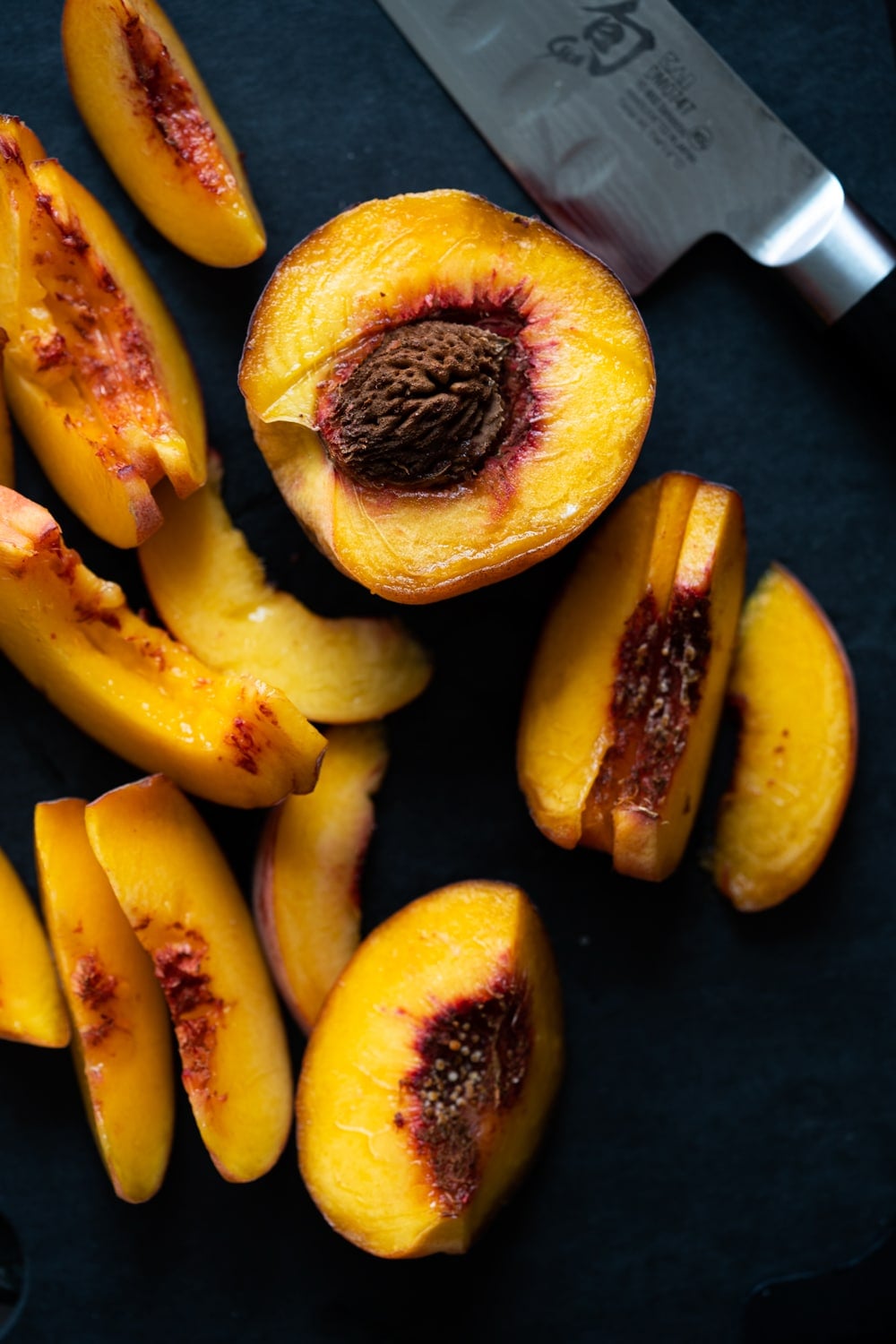 Slicing peaches on a black cutting board